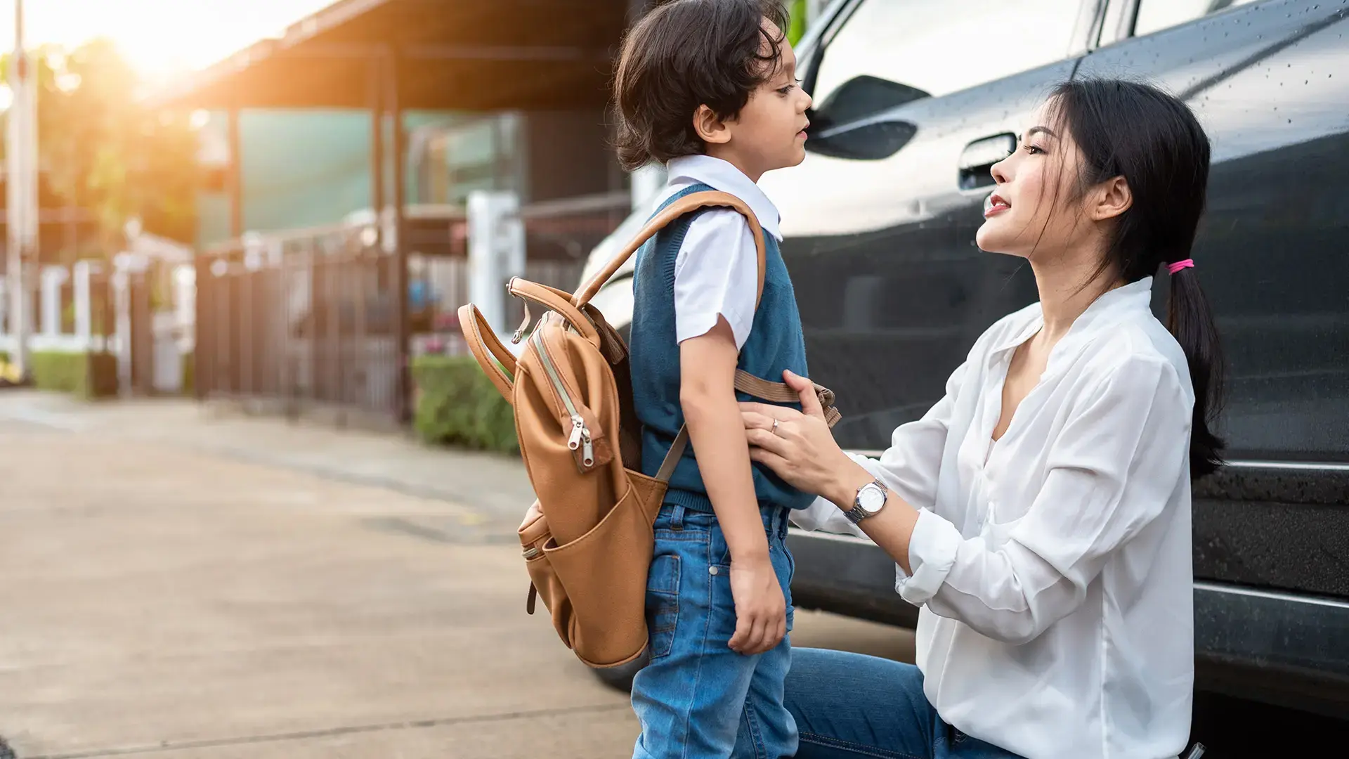 Mother preparing to send her children back to school at car in morning
