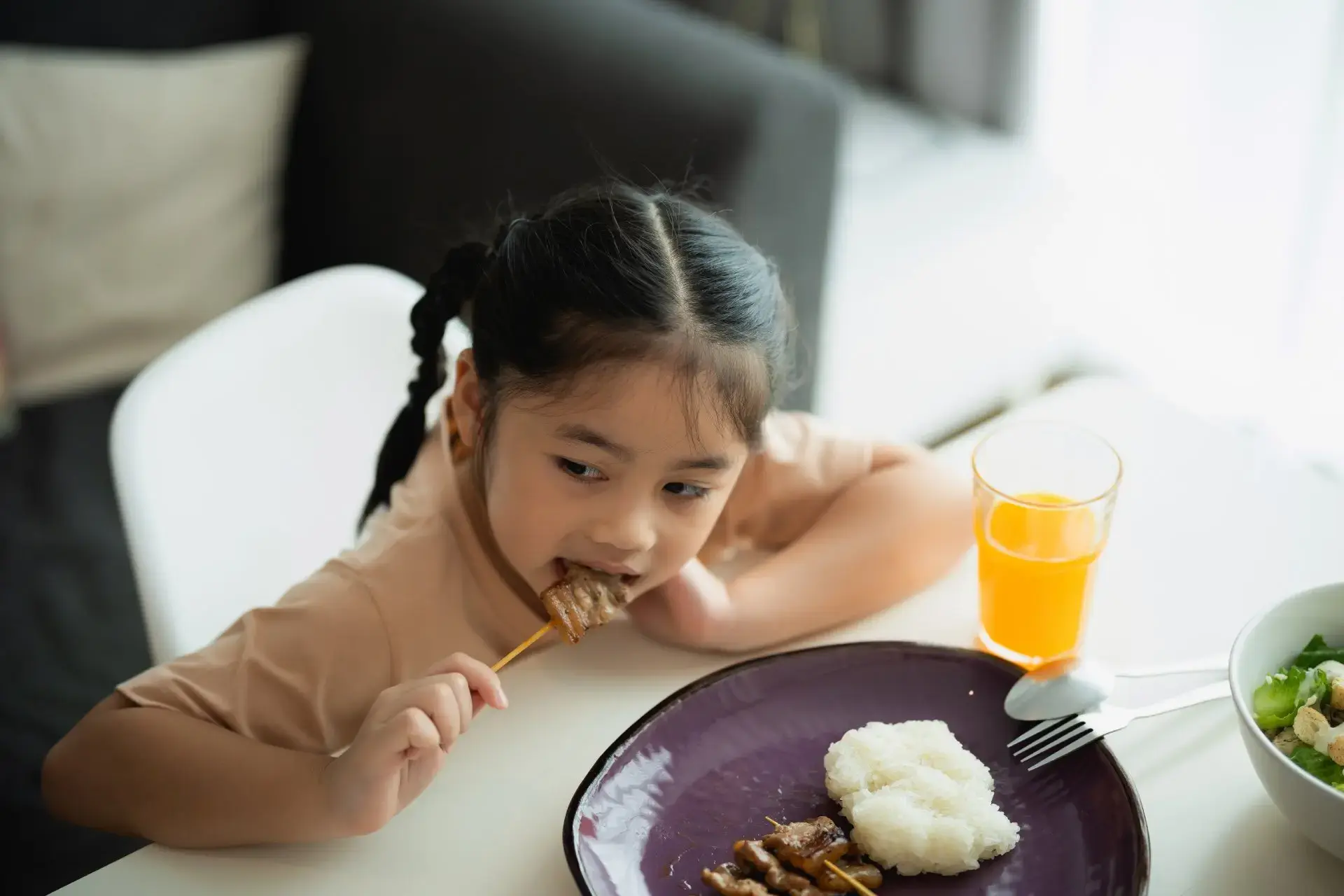 Batang babaeng Asyano na kumakain ng barbecue.