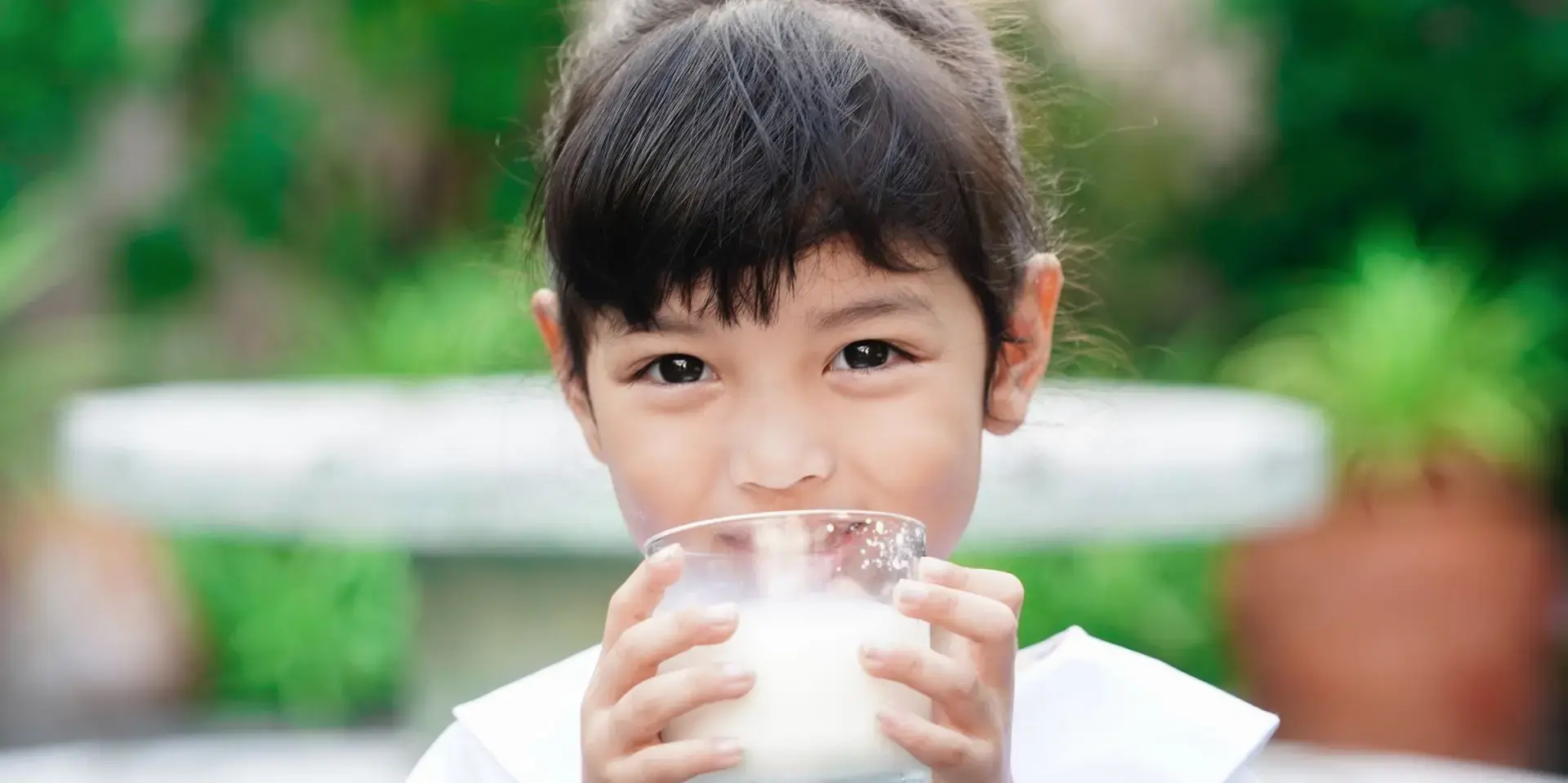 Batang naka-school uniform na umiinom ng gatas.