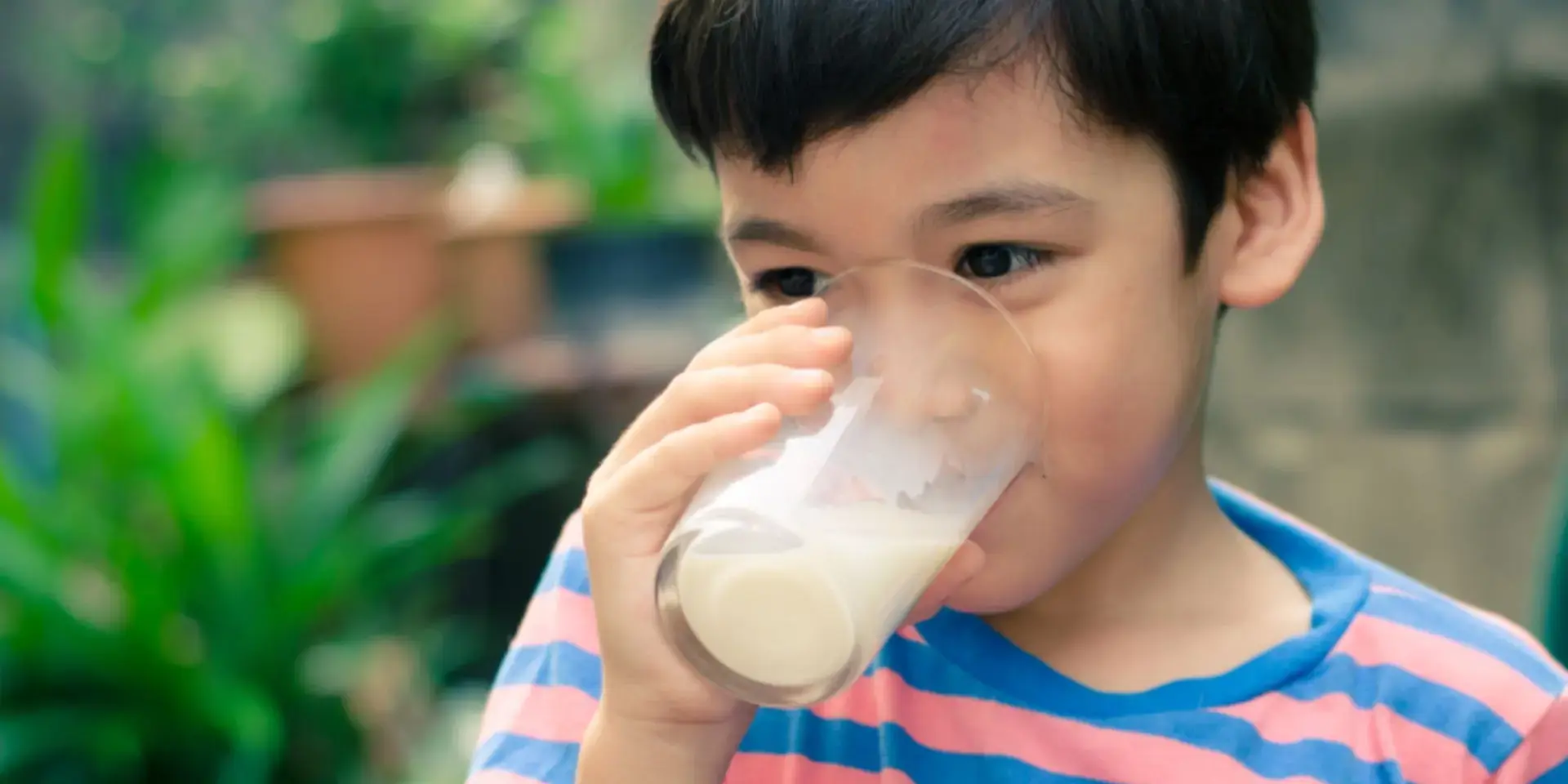 Batang Asyano na umiinom ng isang glass of milk.