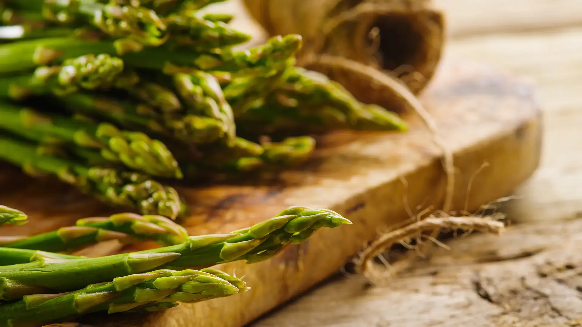 Fresh asparagus on a cutting board and a large skein of twine