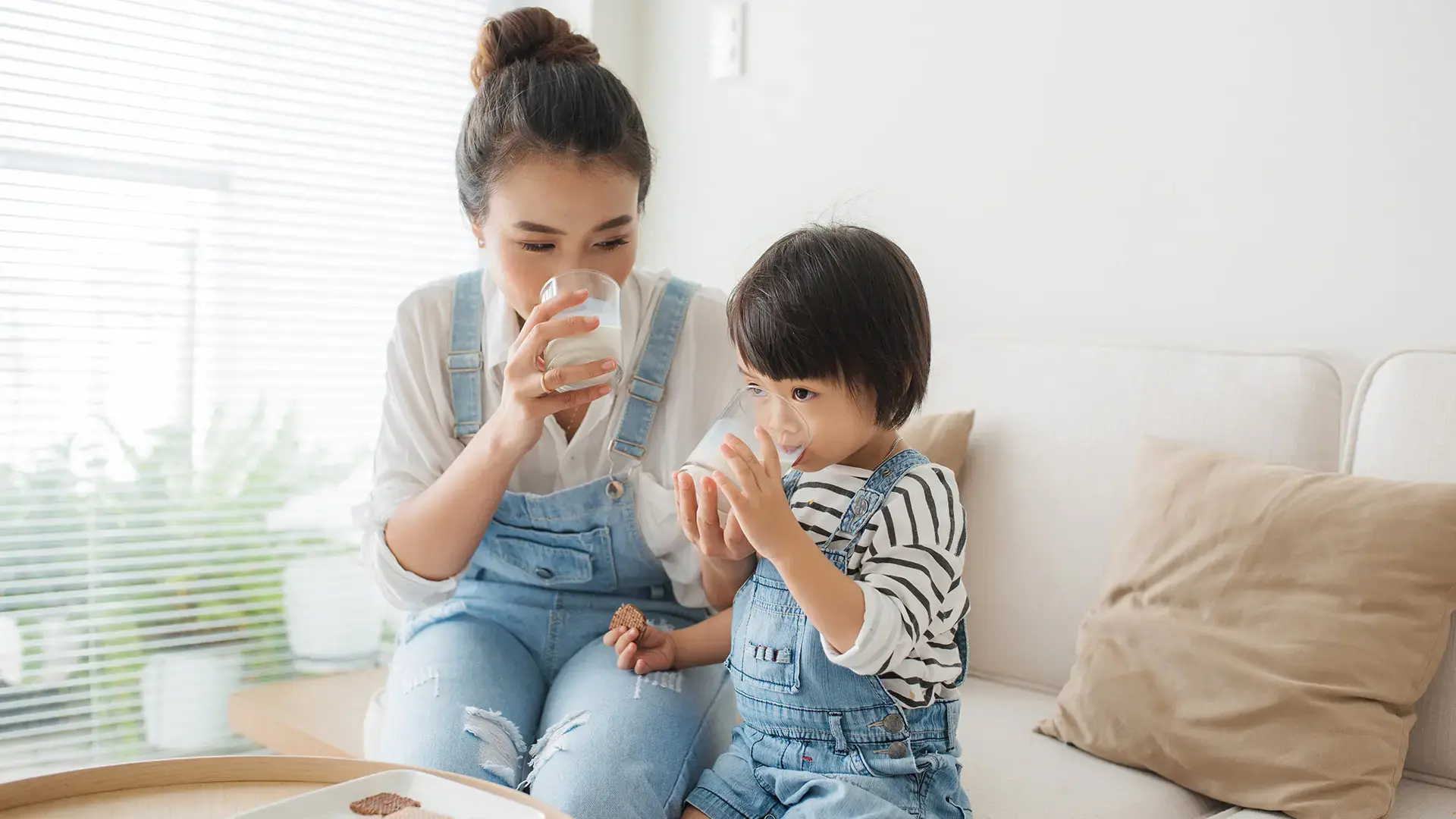 Happy family of asian mom is drinking milk with her cute daughter in the morning at home