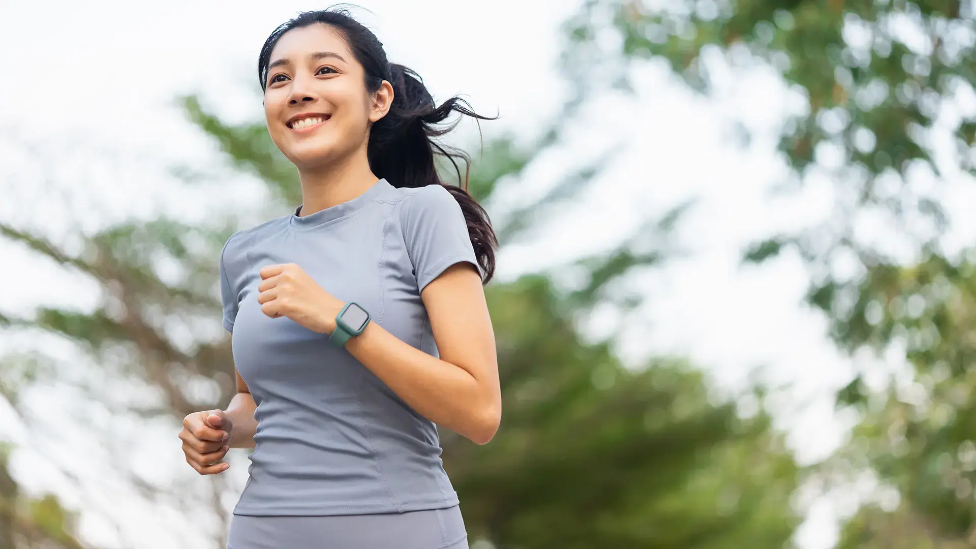 Happy slim woman wearing sportswear jogging in the city at sunrise