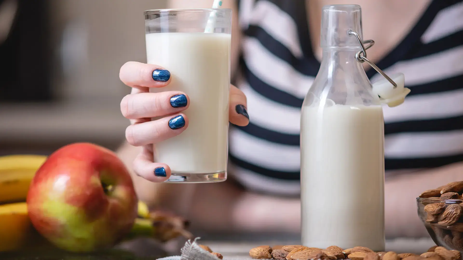 Woman drinking organic almond milk holding a glass in her hand in the kitchen