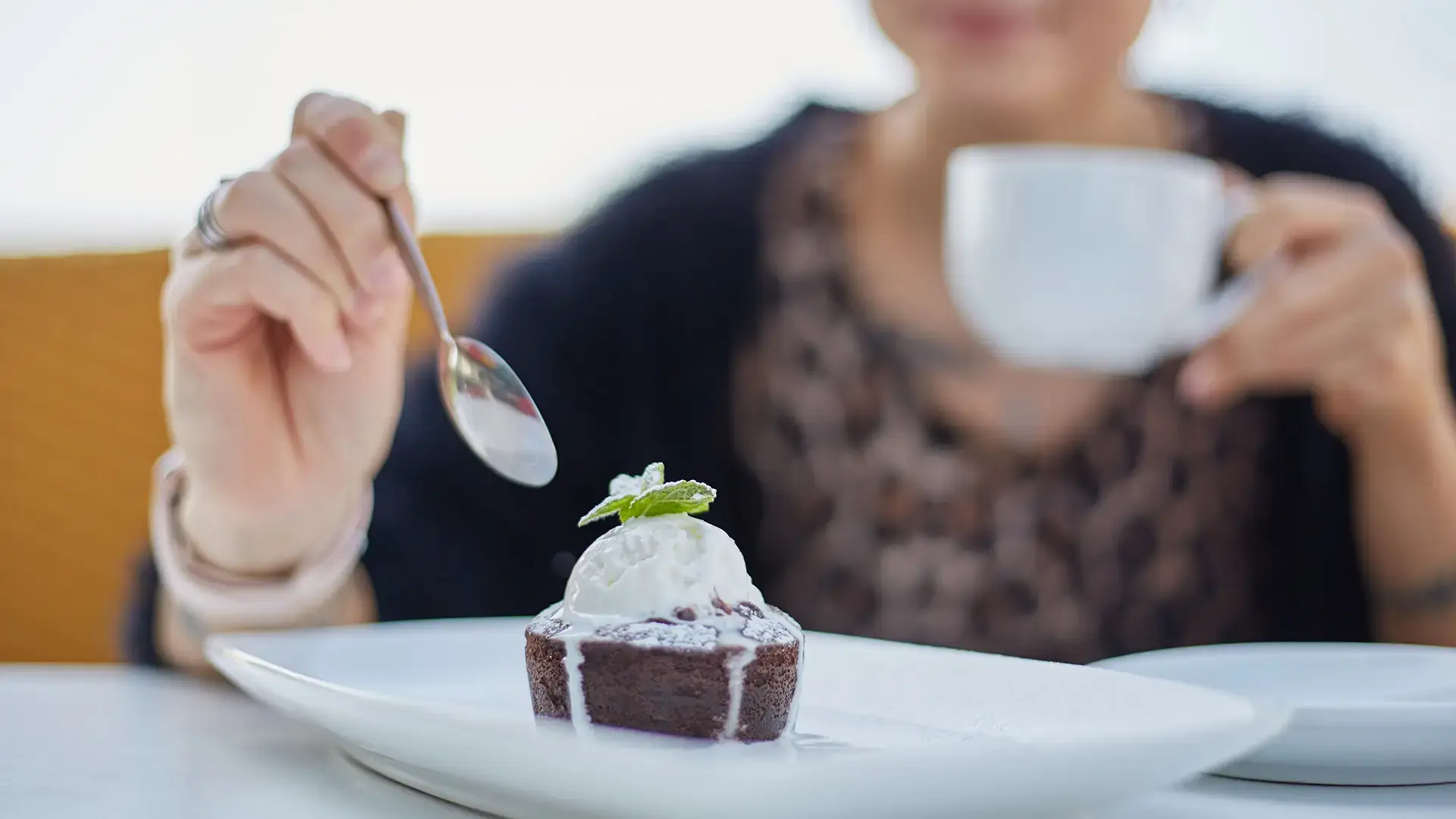 Young woman eating a fondant cake with a cup of coffee in the outdoor restaurant in the morning
