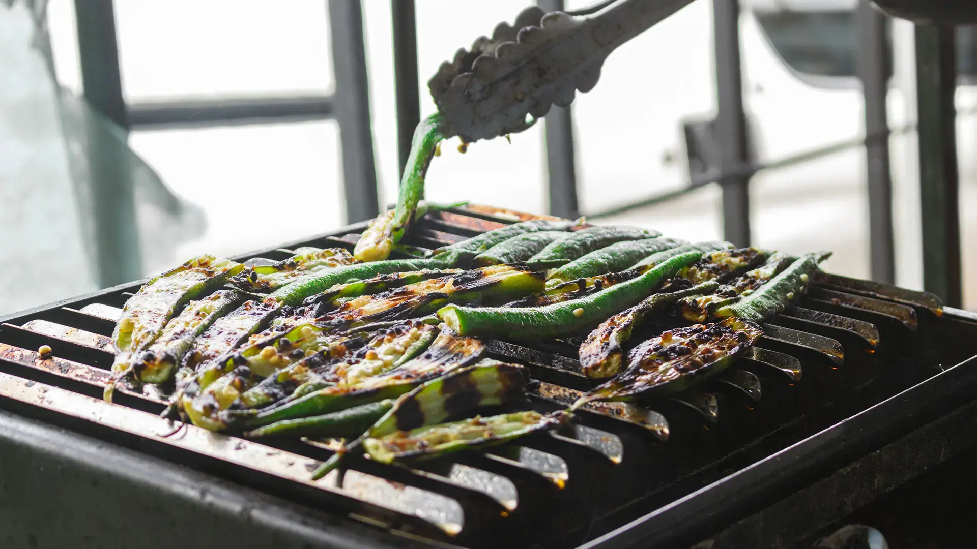 a spatula turning okras on a grill