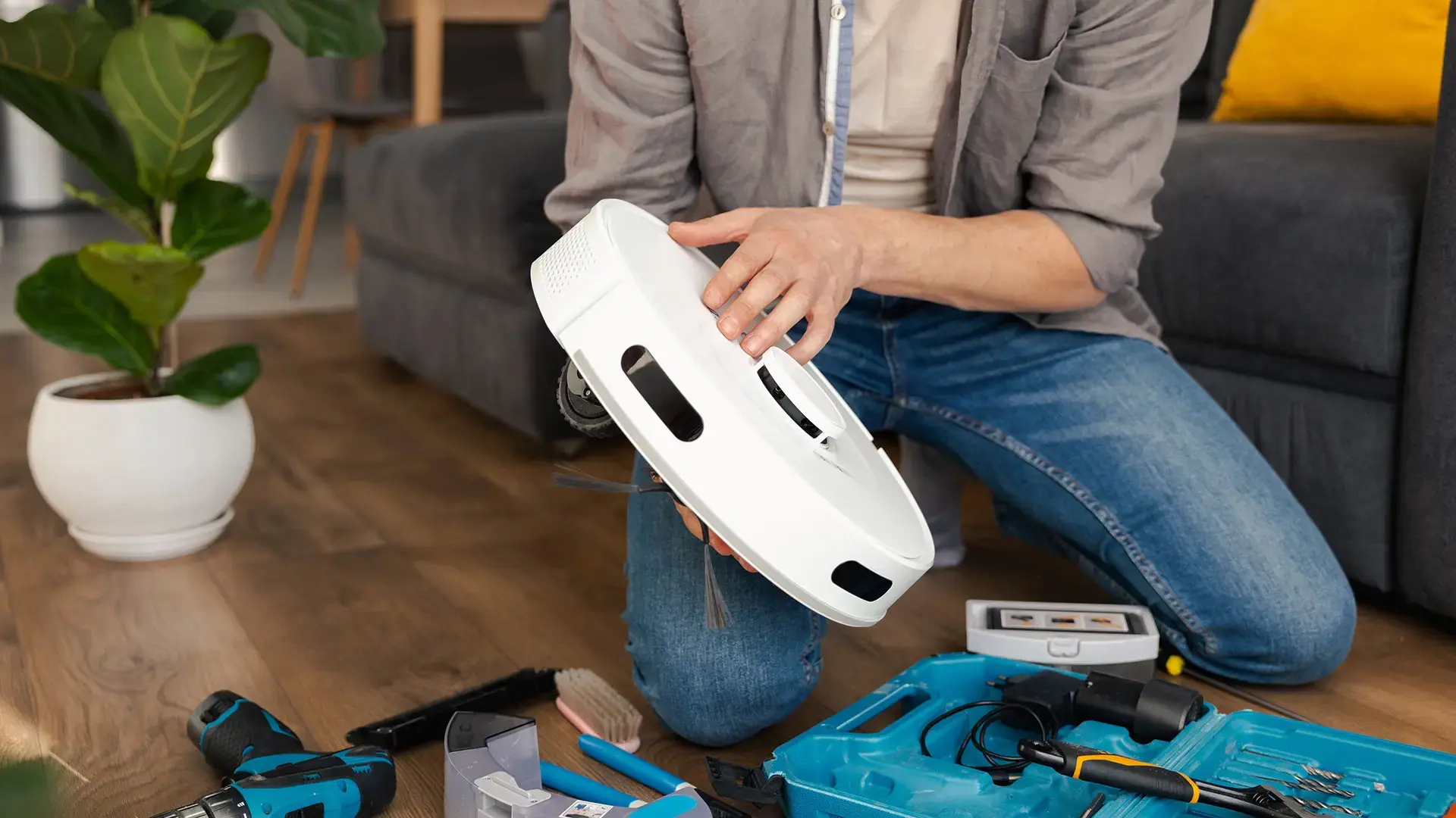 man cleans the container for garbage and dust from a robot vacuum cleaner