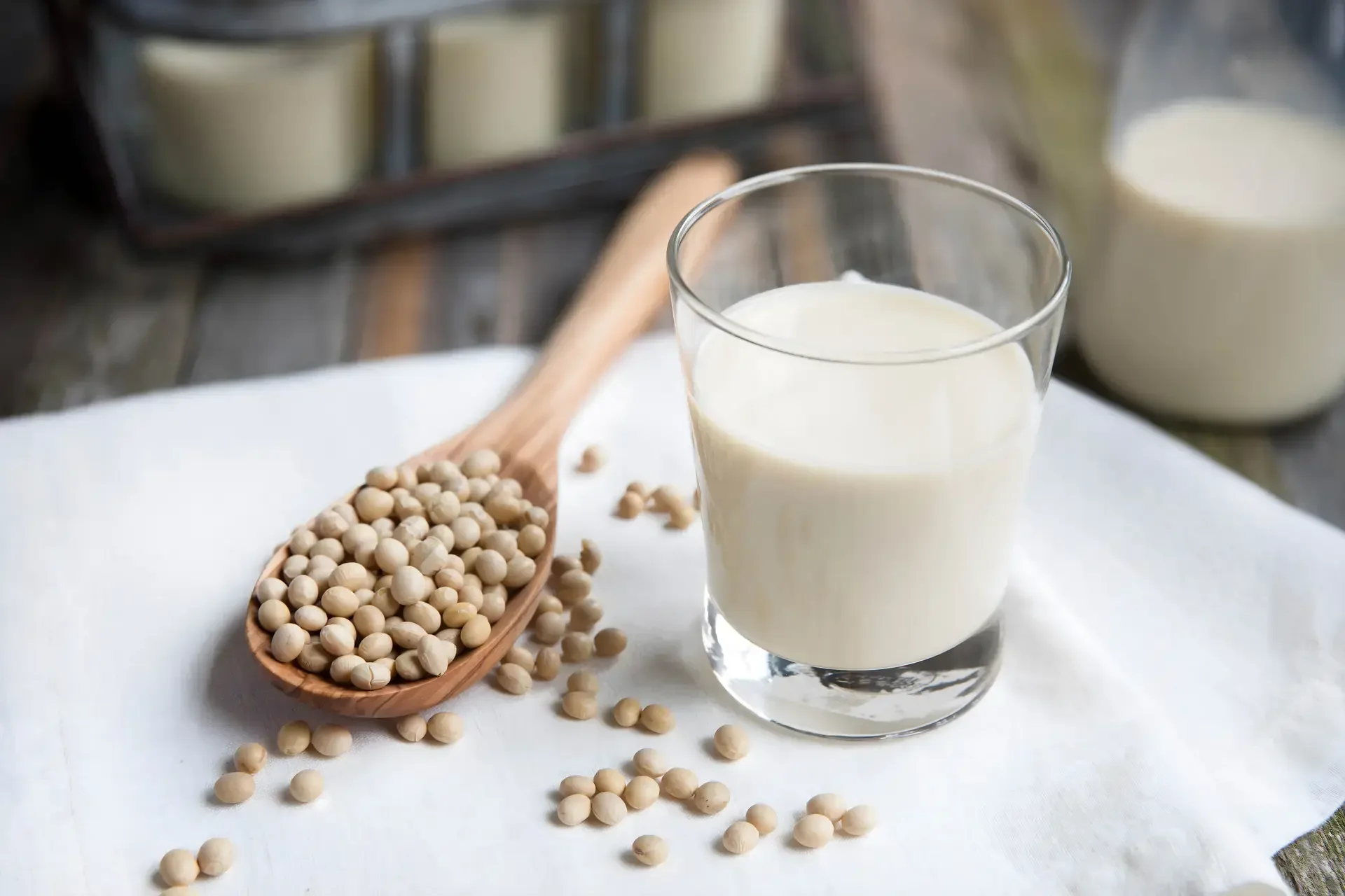 Soybean na nasa isang malaking kutsara at isang basong soy milk.