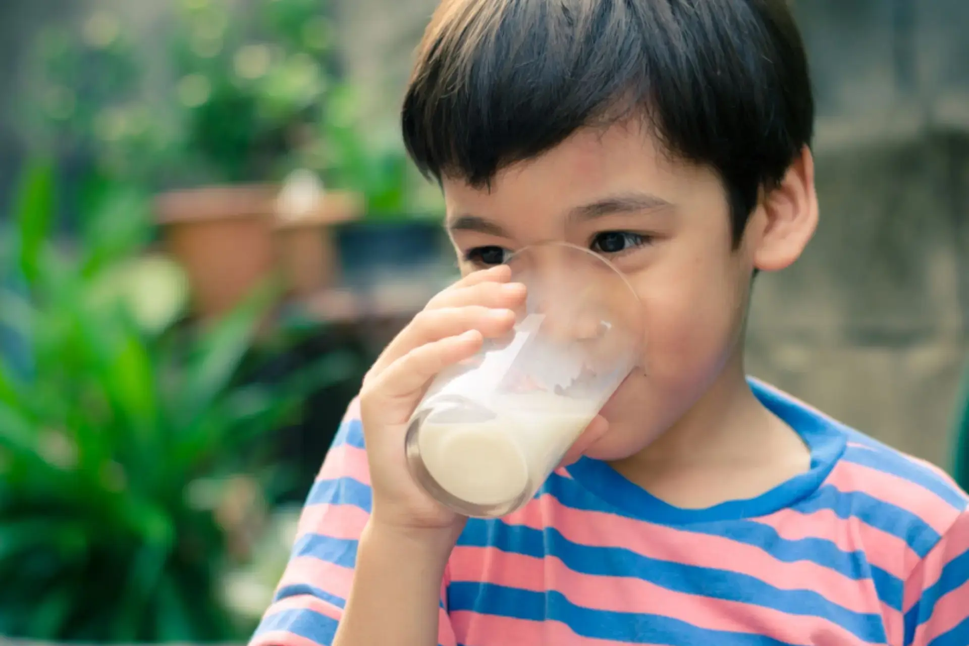 Batang Asyano na umiinom ng isang glass of milk.