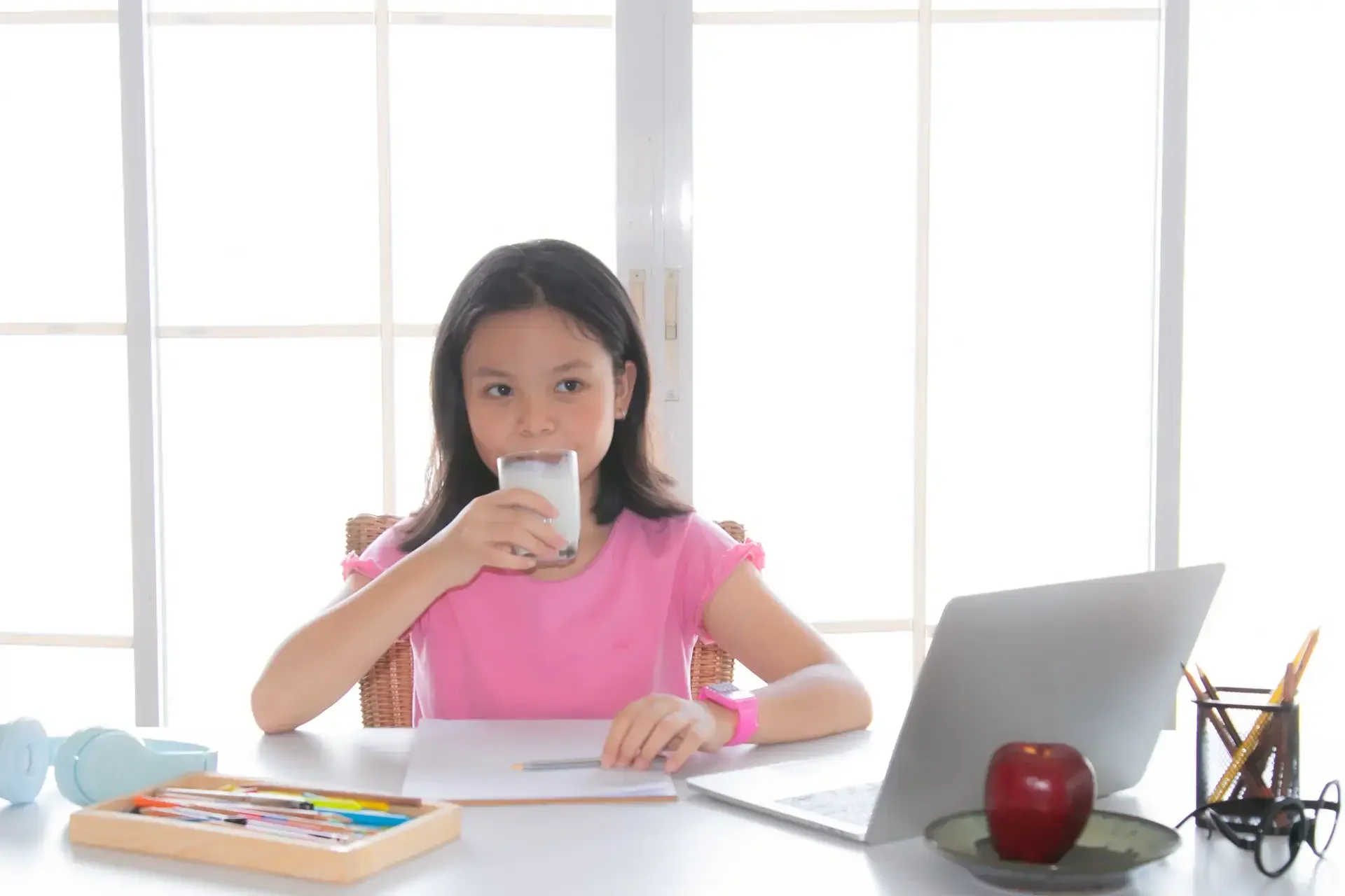 Bata na umiinom ng gatas habang nag-aaral sa kusina.