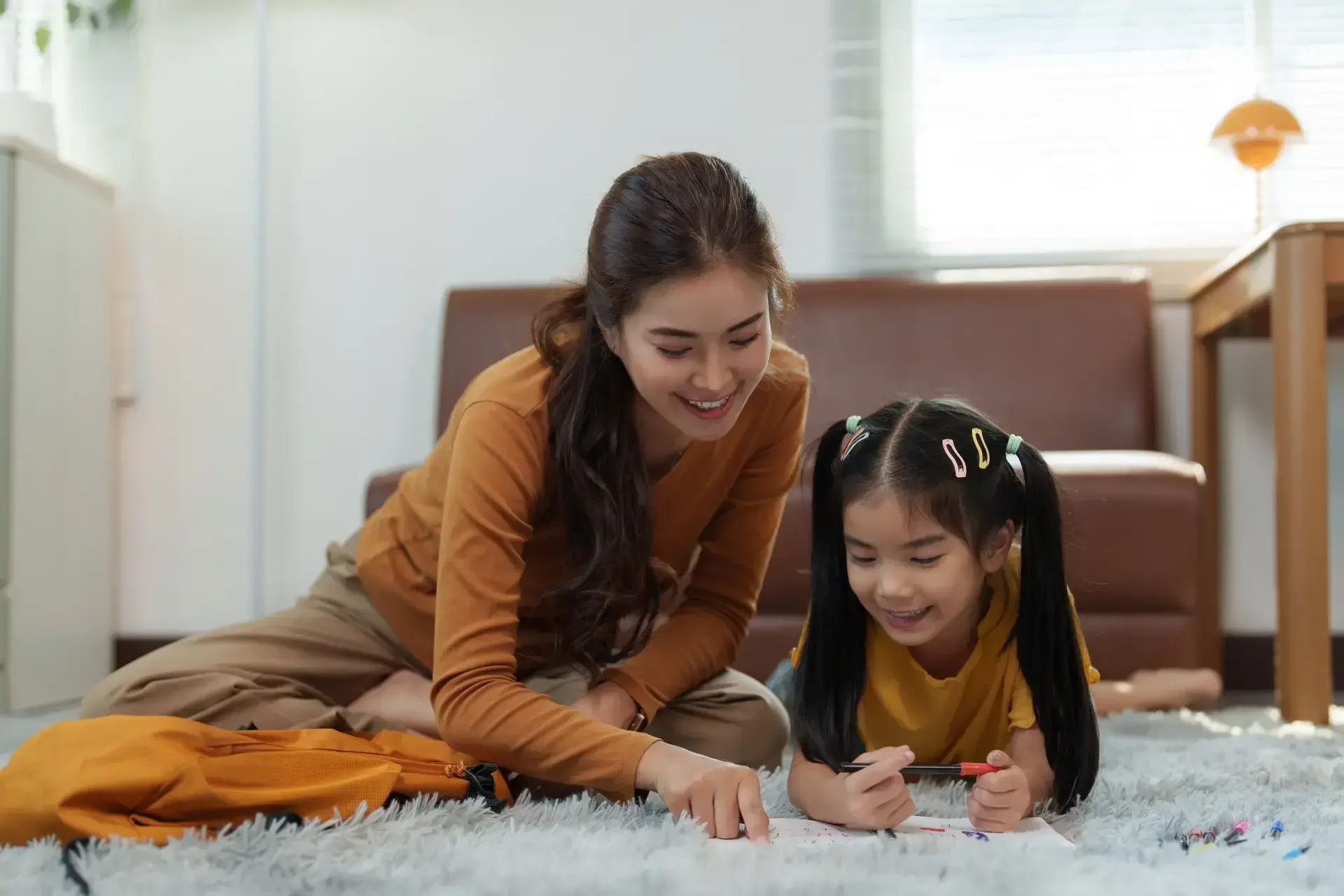 Batang nasa sahig habang nagbabasa ng kuwento kasama ang ina.