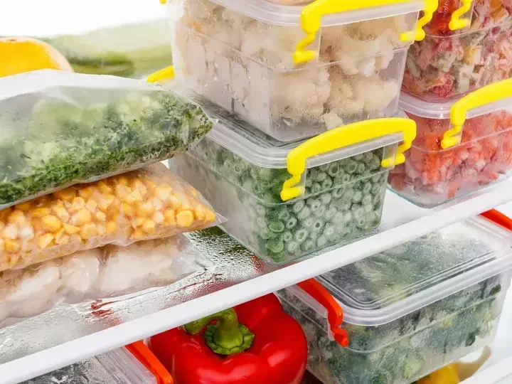 Frozen food in the refrigerator. Vegetables on the freezer shelves.