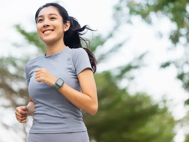 Happy slim woman wearing sportswear jogging in the city at sunrise