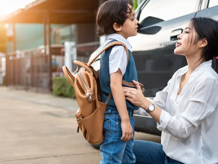 Mother preparing to send her children back to school at car in morning