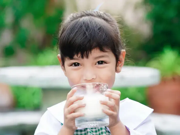 Batang naka-school uniform na umiinom ng gatas.