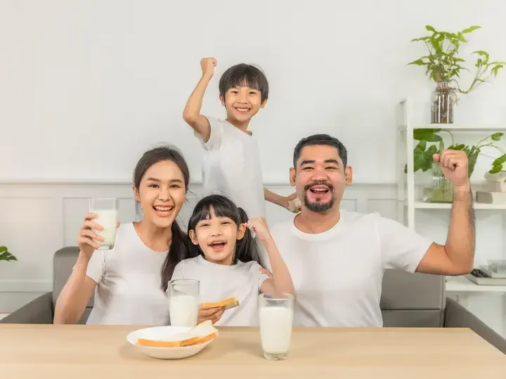 Isang pamilya na umiinom ng gatas at kumakain ng tinapay sa sala.